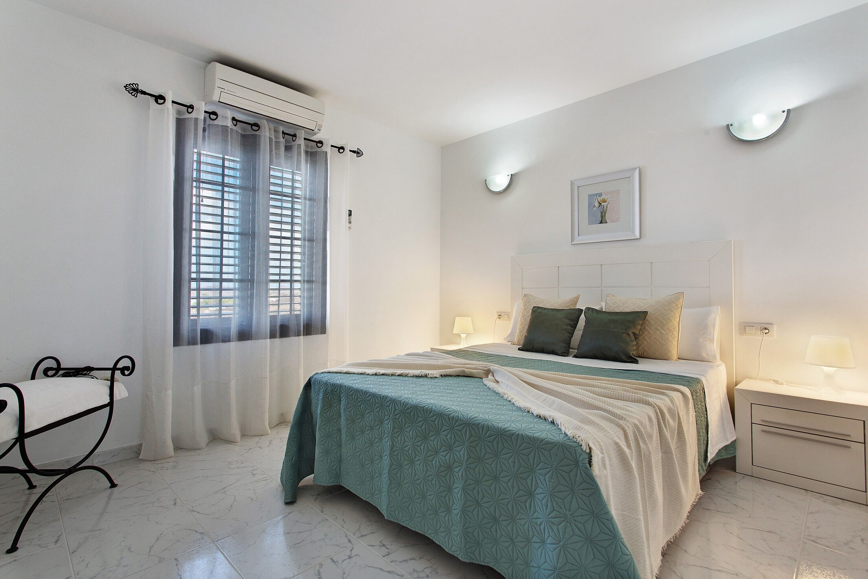 A bedroom with a bed, bedside tables, a chair, and a window with curtains.