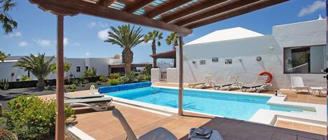 A pool area with lounge chairs and a pergola.