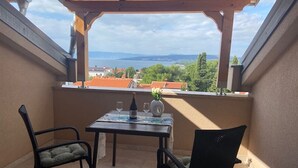 A covered balcony with a table, two chairs, and a view of the sea and buildings. - Apartment in Punat with Seaview, Terrace, Air condition, WIFI (4534-2) (Punat)