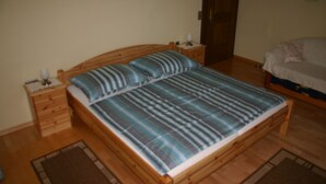 A wooden bed with a striped bedspread, wooden nightstands, and a wooden floor.