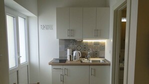 A compact kitchen with a built-in dishwasher, a sink, and a countertop with a kettle and a coffee maker. - Studio with terrace and sea view (Primo šten)