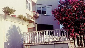 A multi-story building with balconies, a garage, and a pink flowering tree. - Holiday apartment with a balcony and sea view (Primošten)