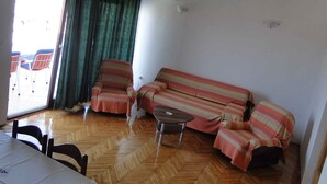A living room with a sofa, two armchairs, a coffee table, and a dining table. - Holiday apartment with a balcony and sea view (Primošten)