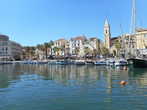 Un port esportiu amb embarcacions amarrades, una torre d'església destacada i una filera d'edificis amb balcons.