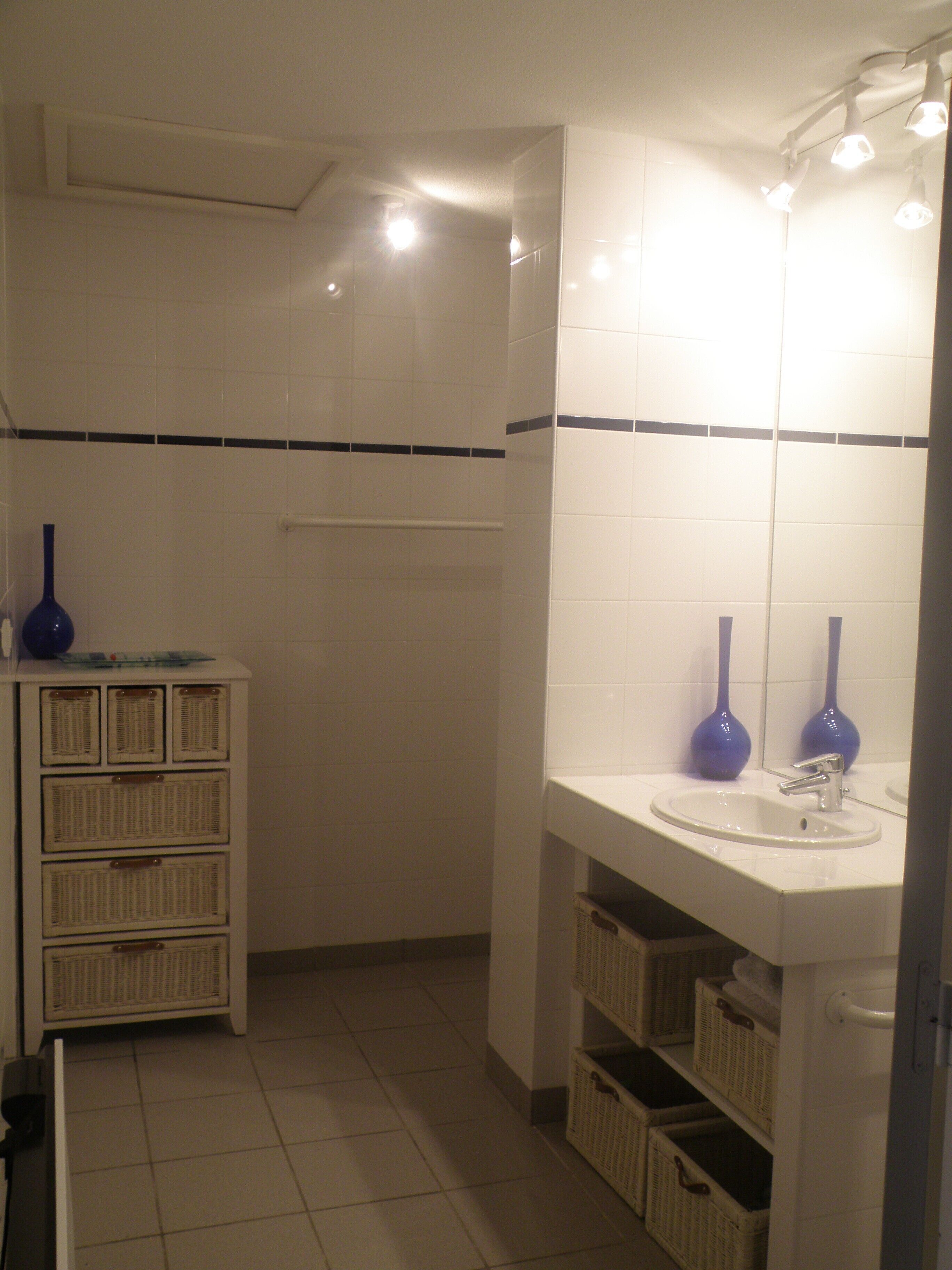 A bathroom with a white sink, two blue vases, and wicker baskets.