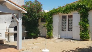 A courtyard with a white door, a small table, and a white pole. - Charming renovated house, near beach and shops (La Faute-sur-Mer)