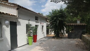 Um pátio com um edifício branco, uma cesta de basquete e vasos de plantas.