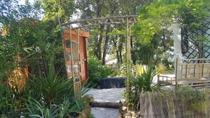 Un sentiero nel giardino conduce a una struttura in legno con un arco di bambù.