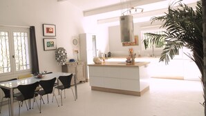Una cucina moderna con isola centrale, zona pranzo con sedie e ampie finestre.