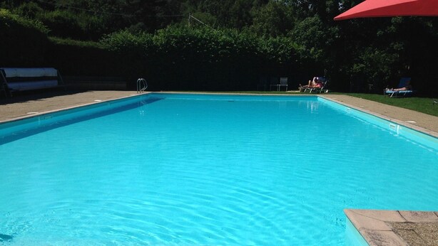 Een rechthoekig zwembad met helderblauw water, omringd door een betonnen terras.