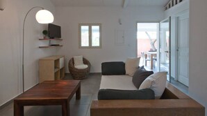A modern living room with a wooden coffee table, a sofa, a wicker chair, and a television on a shelf. - Villa Violetta, 4/5 pers, 2 bedrooms, shared pool in the heart of the Corsican maquis (porto vecchio)
