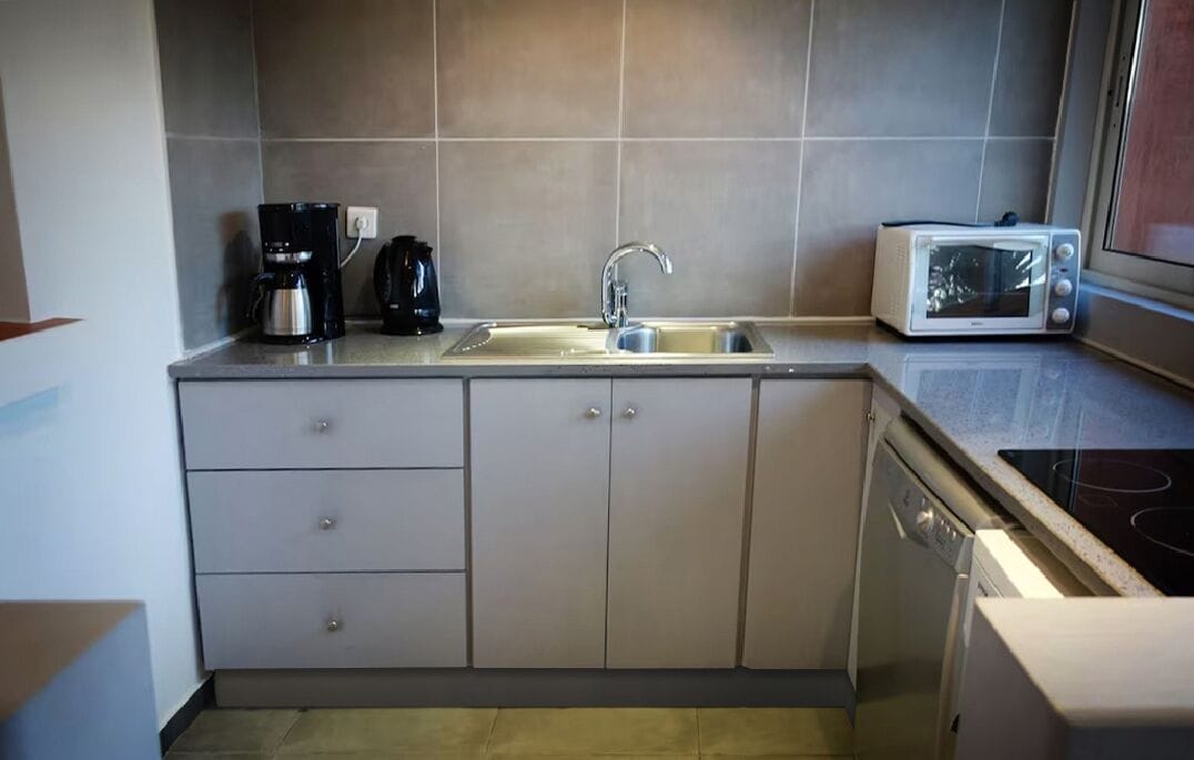 Una cucina compatta con lavello, macchina da caffè, forno a microonde ed elettrodomestici.