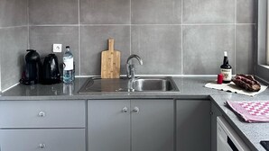 A modern kitchen with grey tiles, a stainless steel sink, and grey cabinets. - Villa Violetta, 4/5 pers, 2 bedrooms, shared pool in the heart of the Corsican maquis (porto vecchio)