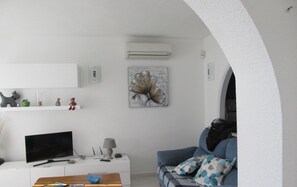 A modern living room with a flat-screen TV, a coffee table, a sofa, and a painting on the wall.