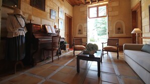 Una habitació amb un piano, cadires, un sofà i una taula amb un ram.