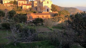 Un village rural doté d’une église imposante, reconnaissable à son clocher, entouré de bâtiments résidentiels et d’une végétation luxuriante.