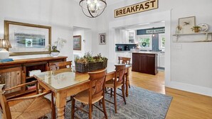 A breakfast area with a wooden table and chairs, a chandelier, and a sign that reads "BREAKFAST". - 2BR COTTAGE IN SANFORD HISTORIC DISTRICT (Sanford)