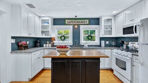 A kitchen with white cabinets, a wooden island, a stove, and a microwave. - 2BR COTTAGE IN SANFORD HISTORIC DISTRICT (Sanford)