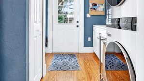 A laundry room with a white door, wooden floor, and a blue wall. - 2BR COTTAGE IN SANFORD HISTORIC DISTRICT (Sanford)