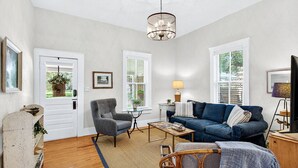 A living room with a sofa, armchair, coffee table, and a chandelier. - 2BR COTTAGE IN SANFORD HISTORIC DISTRICT (Sanford)