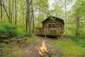 Una cabaña con terraza, rodeada por un bosque.
