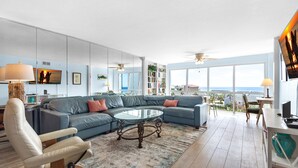 A spacious living room with a large sectional sofa, a glass coffee table, and a view of the ocean through large windows. - 🌅 Cozy Gulf-View Condo | Snowbird Rates & Sauna | Shoreline 3063 (Destin)