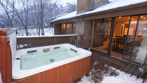 Ett bubbelbad på ett trädäck med snö på marken.