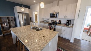 A modern kitchen with granite countertops, stainless steel appliances, and white cabinetry.