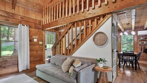 A wooden cabin interior with a sofa, dining table, and staircase. - Falling Leaf Cabin Rustic Charm With Modern Decor! High Speed Internet!  (Rileyville)