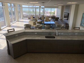 Relax in a spacious room with a curved counter, seating area, and large windows offering a view of the outdoors and balcony.