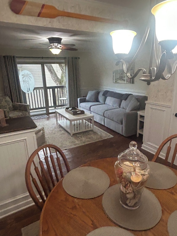 A cozy living room with a dining table, a sofa, and a ceiling fan.