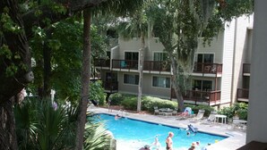 A swimming pool surrounded by palm trees and a multi-story building with balconies. - Updated poolside villa, short walk to beach and Coligny Plaza (Hilton Head Island)