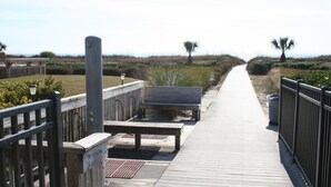 A wooden boardwalk leading to a beach area with benches and a trash can. - Updated poolside villa, short walk to beach and Coligny Plaza (Hilton Head Island)