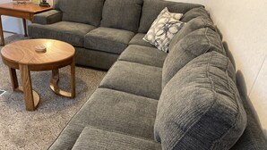Ein modulares Sofa mit einem runden Couchtisch, einem gemusterten Zierkissen und einem kleinen Beistelltisch.