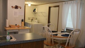 Eine kleine Küche mit Spüle, Arbeitsplatte und Essbereich mit Stühlen.