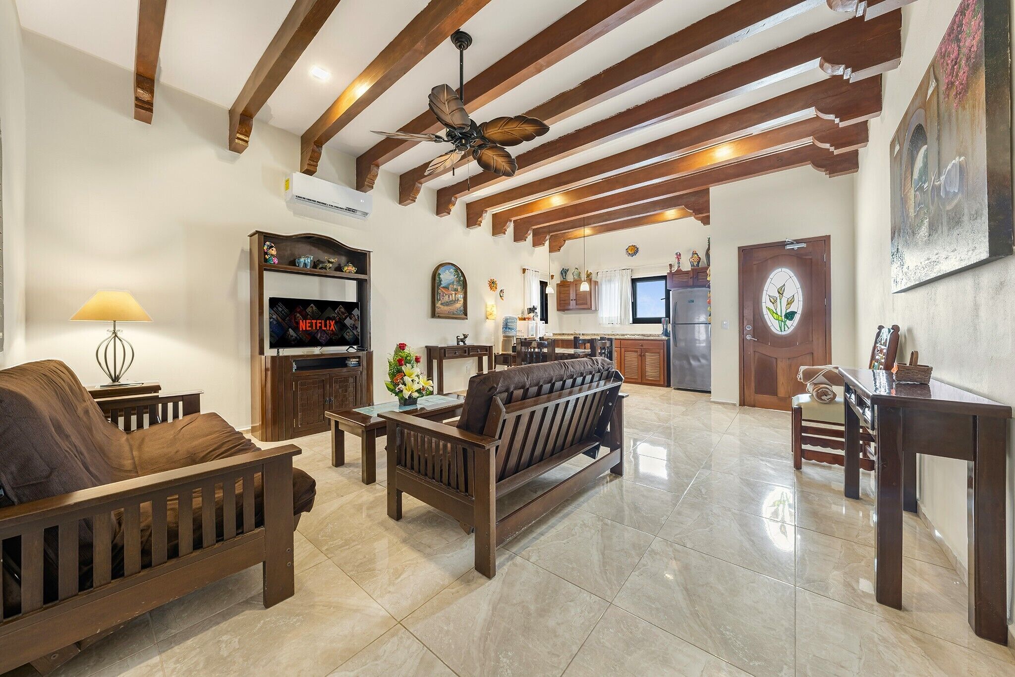 A spacious living room with a sofa, a coffee table, and a TV displaying 'NETFLIX'.