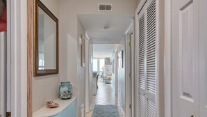A hallway with a tiled floor, a vase, and a mirror on the left wall. - +Serenity by the Sea+, Family Friendly, Best Views/ Location, Direct OF Corner! (Myrtle Beach)