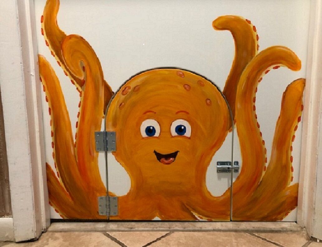 A bathroom with a large, cartoonish octopus mural on the wall.