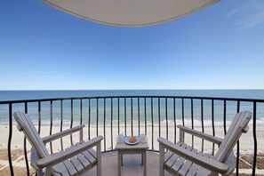 A balcony with two Adirondack chairs and a small table with a plate and two cups. The view includes a beach and the ocean. - +Serenity by the Sea+, Family Friendly, Best Views/ Location, Direct OF Corner! (Myrtle Beach)