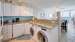 A kitchen with white cabinets, a built-in dishwasher, a washing machine, and a granite countertop. - +Serenity by the Sea+, Family Friendly, Best Views/ Location, Direct OF Corner! (Myrtle Beach)