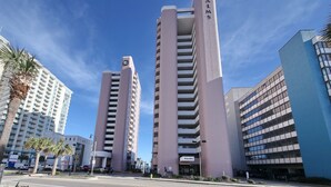 Two tall buildings with the name 'PALMS' on them, surrounded by palm trees and other buildings. - +Serenity by the Sea+, Family Friendly, Best Views/ Location, Direct OF Corner! (Myrtle Beach)