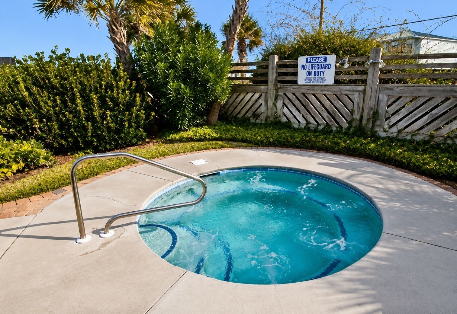 A swimming pool with a metal ladder, surrounded by a wooden fence and greenery.