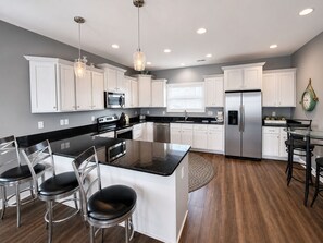 A modern kitchen with white cabinets, stainless steel appliances, and a central island with bar stools.