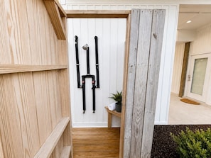 A wooden door with black straps, a small shelf with a plant, and a wooden bench.
