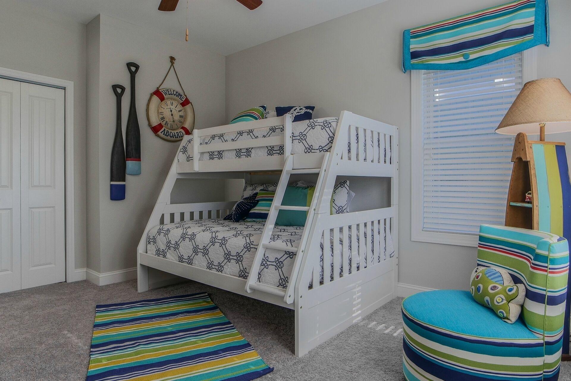 A bunk bed with a ladder, a striped rug, a striped pillow, and a lamp.