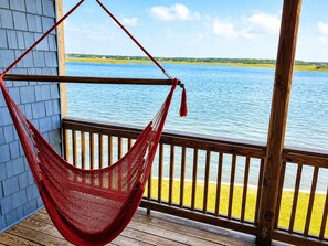 A hammock on a wooden deck overlooking a body of water.