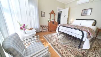 A bedroom with a bed, a chair, a dresser, and a mirror.