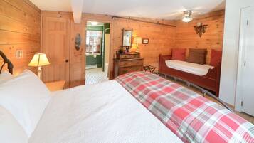 A wooden room with a bed, a dresser, a mirror, and a door.
