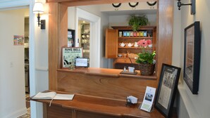 A reception desk with a mirror, a sign for 'Ring Bell for Service', and a framed picture on the wall. - The Springwater B&B (Saratoga Springs)