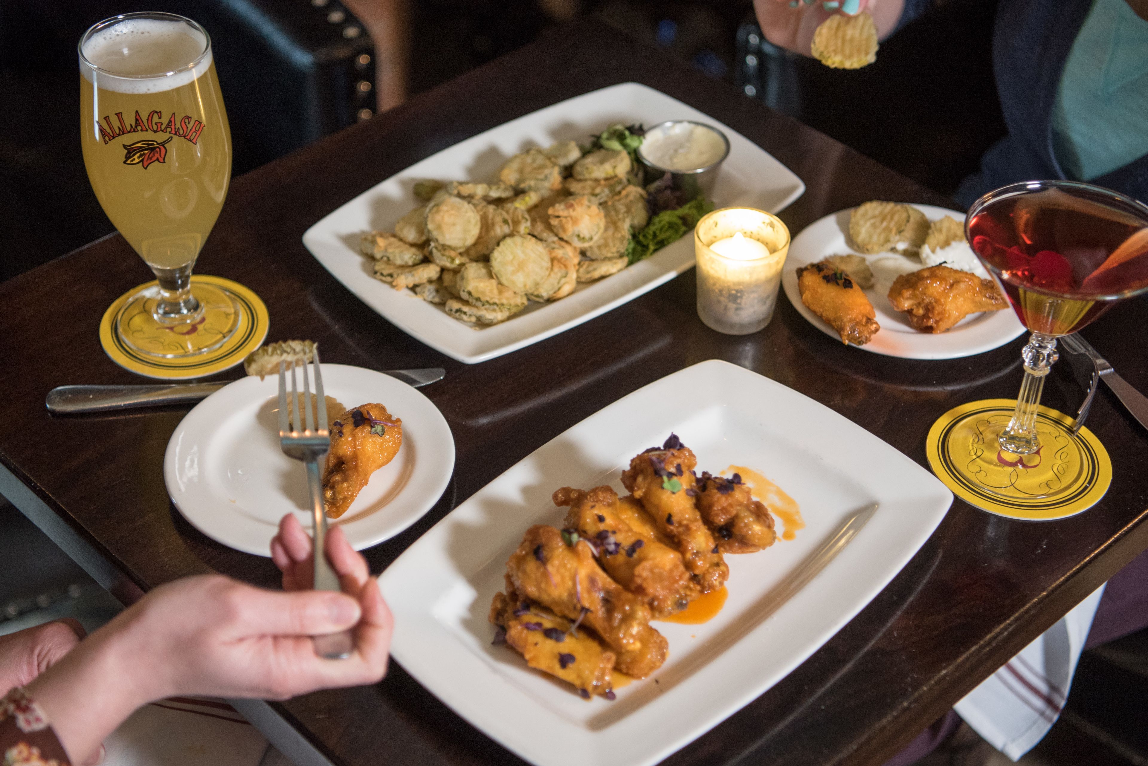 A dining table with various dishes, a glass of beer, and a candle.